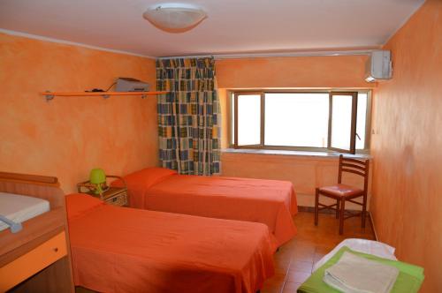 焦约萨马雷阿Giocasa的一间卧室设有两张床、一个窗口和椅子