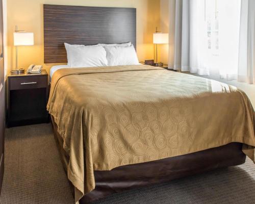 伊姆派瑞尔匹兹堡机场柱石套房酒店的一张大床,位于酒店带两盏灯的房间