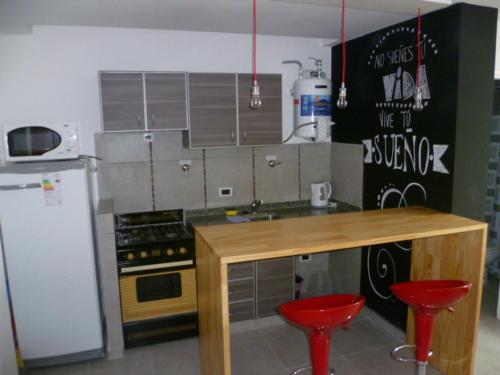 玛利亚镇Departamento Corrientes的厨房配有2张红色凳子和木制柜台。