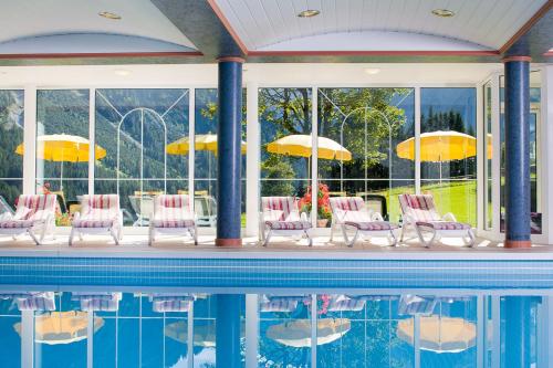 米特尔贝格莱特纳酒店的一个带桌椅和遮阳伞的游泳池