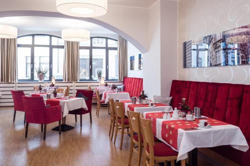 波恩Hotel Deutsches Haus的一间带桌椅和红色摊位的餐厅