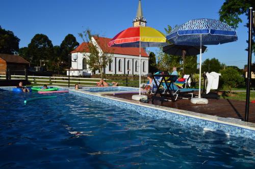 新彼得罗波利斯蒲萨达皮哈勒奥拓酒店的游泳池,游泳池里有人坐在雨伞下
