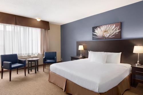 多瓦尔戴斯酒店及会议中心 - 蒙特利尔机场的酒店客房带一张床、一张桌子和椅子