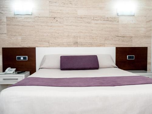 Argamasilla de Calatrava斯夸尔斯克鲁兹酒店的卧室配有一张白色大床和紫色枕头