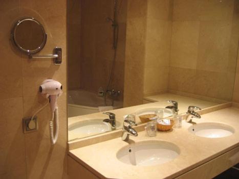 萨莫拉多纳沃卡酒店的浴室设有两个盥洗盆,镜子旁设有电话