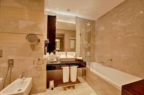 丹吉尔市中心皇家金色郁金香酒店的一间带水槽、浴缸和卫生间的浴室