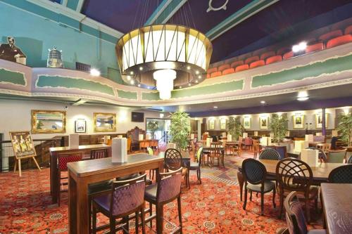 马奇The Hippodrome Wetherspoon的一间带桌椅和吊灯的餐厅