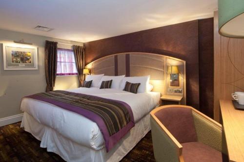 罗切斯特威瑟斯本金狮酒店的酒店客房带一张大床和一把椅子