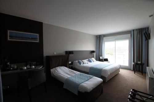 康村Hôtel Le Cheval Blanc的酒店客房设有两张床和窗户。