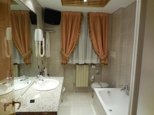 切萨诺博斯科内罗马酒店的浴室配有2个盥洗盆、浴缸和浴缸。