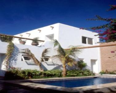 卡波圣卢卡斯Los Milagros Hotel的一座白色的建筑,拥有棕榈树和一个游泳池