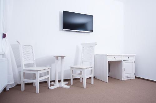 斯维塔维Hotel Slavia的一间设有白色椅子、书桌和电视的客房
