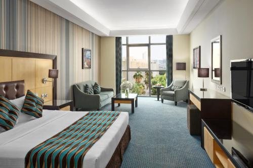 利雅德RAND by Wandalus的酒店客房配有床、椅子和电视。