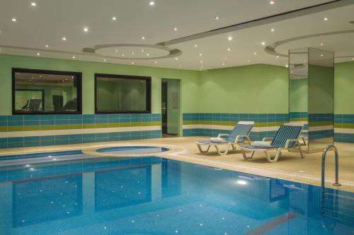 利雅德RAND by Wandalus的一个带两把椅子的酒店游泳池和一个游泳池