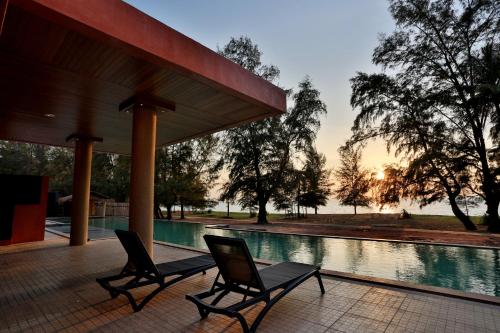 迈考海滩Coriacea Beachfront Boutique Phuket Resort - SHA Plus的游泳池旁几把椅子