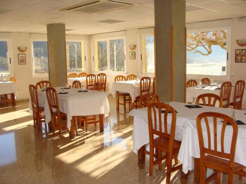 科利德纳尔戈Hotel Del Llac的用餐室配有白色的桌子和木椅