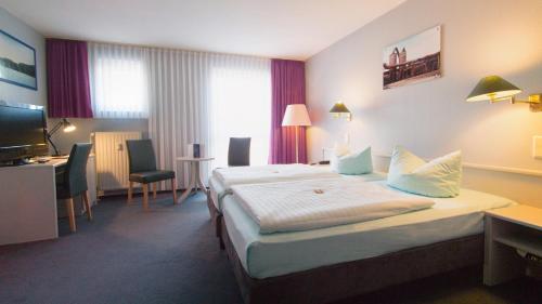 波鸿波鸿伊克赛尔瑟酒店的配有一张床和一张书桌的酒店客房