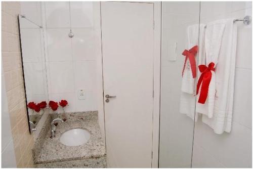 泰谢拉迪弗雷塔斯Hotel QualitySul的浴室设有水槽和带红色弓的淋浴。