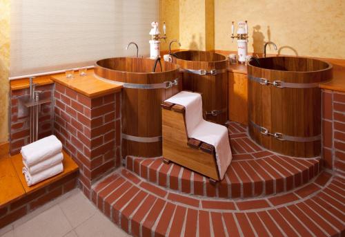 奥洛穆茨奧洛穆克克拉丽奥国会酒店的浴室设有3个木制浴缸和椅子