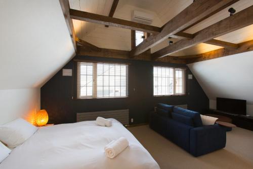 二世古灰岩度假屋的一间卧室配有一张大床和一张蓝色的沙发