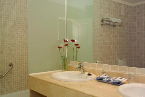 贝纳尔马德纳假日世界度假酒店的浴室设有水槽、镜子和鲜花