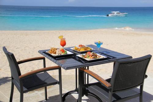 Meads Bay卡里玛尔海滩俱乐部 的海滩上一张桌子,上面放着两盘食物
