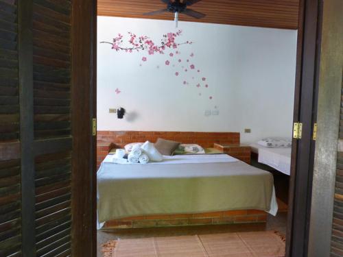 乌巴图巴Suítes o Flautista的卧室配有一张墙上鲜花的床
