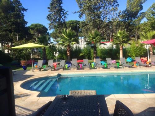 拉特斯Hotel & Restaurant Le Mejean - Parc des Expositions的一个带椅子和遮阳伞的游泳池以及棕榈树