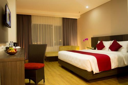 贝克西Merapi Merbabu Hotels Bekasi的酒店客房配有一张床铺、一张桌子和一张书桌。