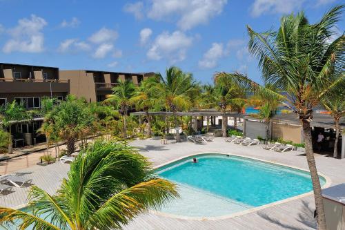 克拉伦代克伊甸海滩度假村 - 博内亚的一座棕榈树和椅子的游泳池以及一座建筑