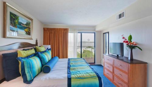 德斯坦Bay Club of Sandestin, a VRI resort的一间卧室配有一张带电视的床和梳妆台。