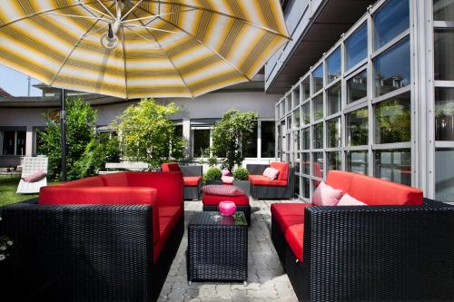 伯尔尼拉裴格拉伯尔尼酒店的一个带红色家具和雨伞的庭院