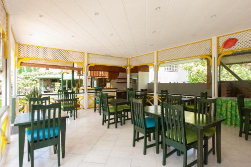 拉迪格岛米歇尔旅馆的餐厅设有绿色的椅子和桌子以及窗户。