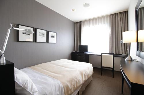 上田市Sotetsu Fresa Inn Nagano-Ueda的配有一张床、一张书桌和一扇窗户的酒店客房