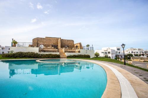 迦玛特Golden Carthage Residences的一个大型蓝色游泳池,其建筑背景为: