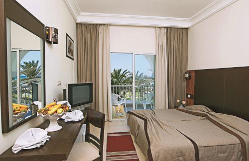 马赫迪耶El Mehdi Beach Resort ex Primasol El Mehdi的酒店客房配有一张床和一张书桌及一台电视