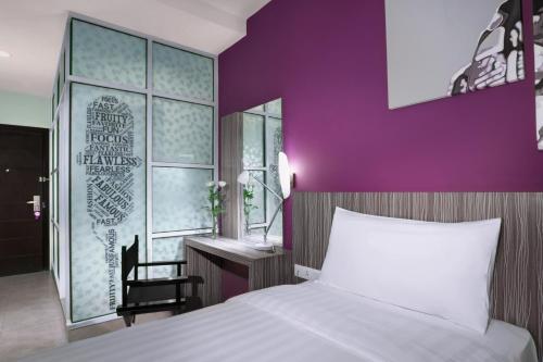 Batu AjiOS Style Hotel Batam Powered by Archipelago的卧室配有白色的床和紫色墙壁