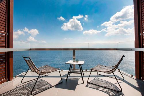 伊罗达Aquila Elounda Village Resort, Suites & Spa的阳台上配有两把椅子和一张桌子,享有海景