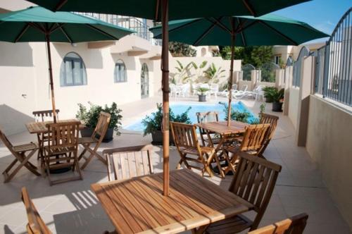 San Ġwann卡帕拉酒店的庭院配有木桌、椅子和遮阳伞