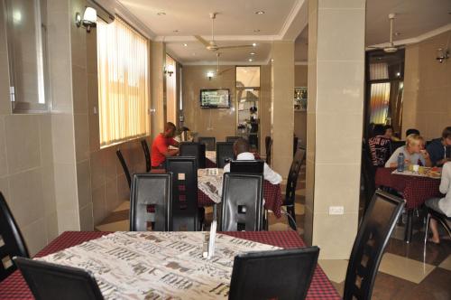 阿鲁沙里奇酒店的一间设有桌子的餐厅,有坐在桌子上的人
