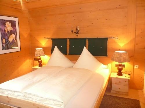 措布伦Chalet Tannheimer Tal的一间卧室配有一张带两盏灯的大型白色床。