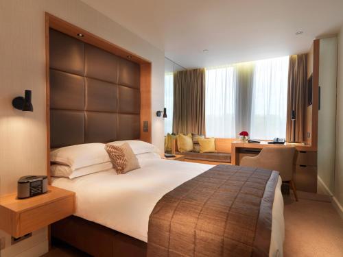 伦敦皇家花园酒店的一间卧室配有一张大床和一张书桌