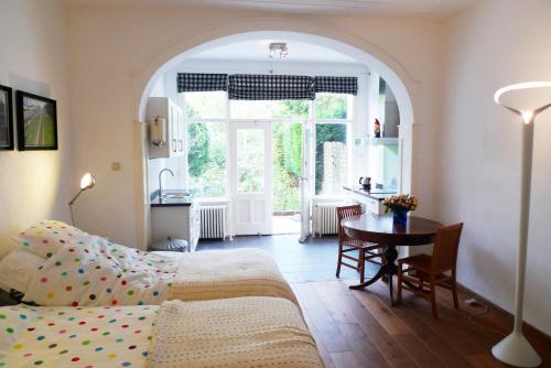 鹿特丹瓦尔恩贝格住宿加早餐酒店的一间卧室配有一张床铺和一张桌子,还设有一间厨房