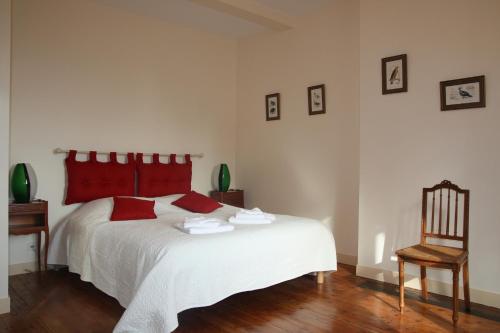 圣艾尼昂La maison de Léonard, Aux grilles du Château de Saint-Aignan, à 2km de Beauval的卧室配有白色的床、红色枕头和椅子