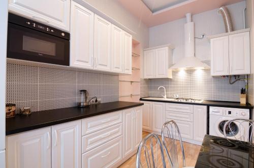 利沃夫LEOGRAND Apartments on Doroshenka 34的白色的厨房配有白色橱柜和黑色台面