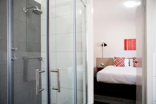 Villawood维拉伍德酒店的一间带玻璃淋浴间和床的浴室
