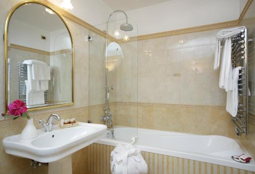 罗马万神殿酒店的一间带水槽、浴缸和镜子的浴室
