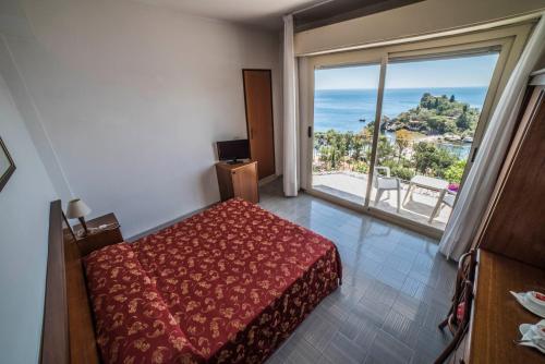 陶尔米纳伊索拉贝拉酒店的一间卧室设有一张床和一个大窗户