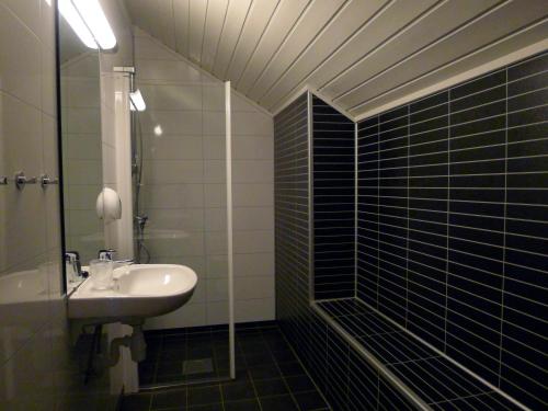 Jostedal加斯特代尔酒店的黑色瓷砖浴室设有水槽和淋浴