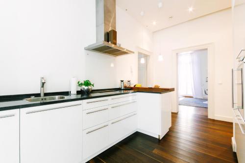 巴登-巴登Deluxe Apartments LWP7的厨房铺有木地板,配有白色橱柜。